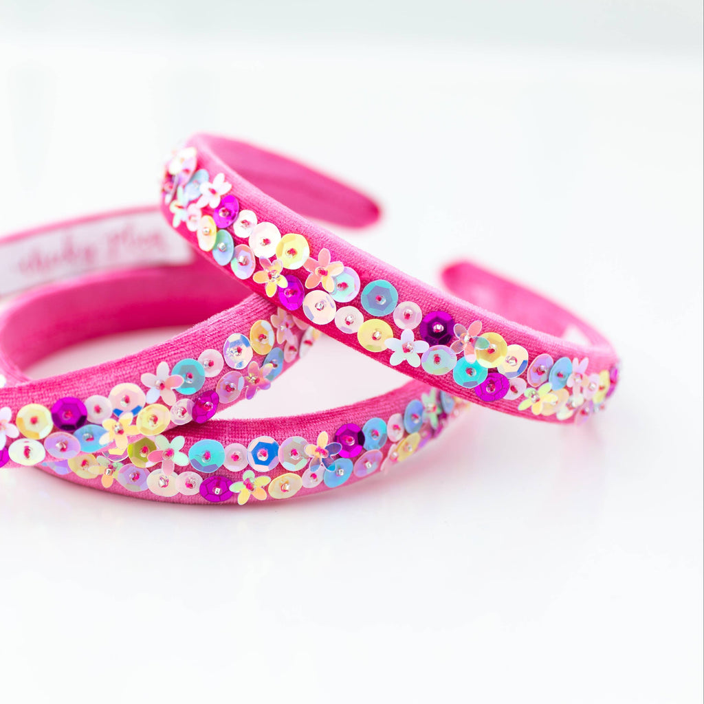 Pink headbands with colorful sequin flowers on a white background