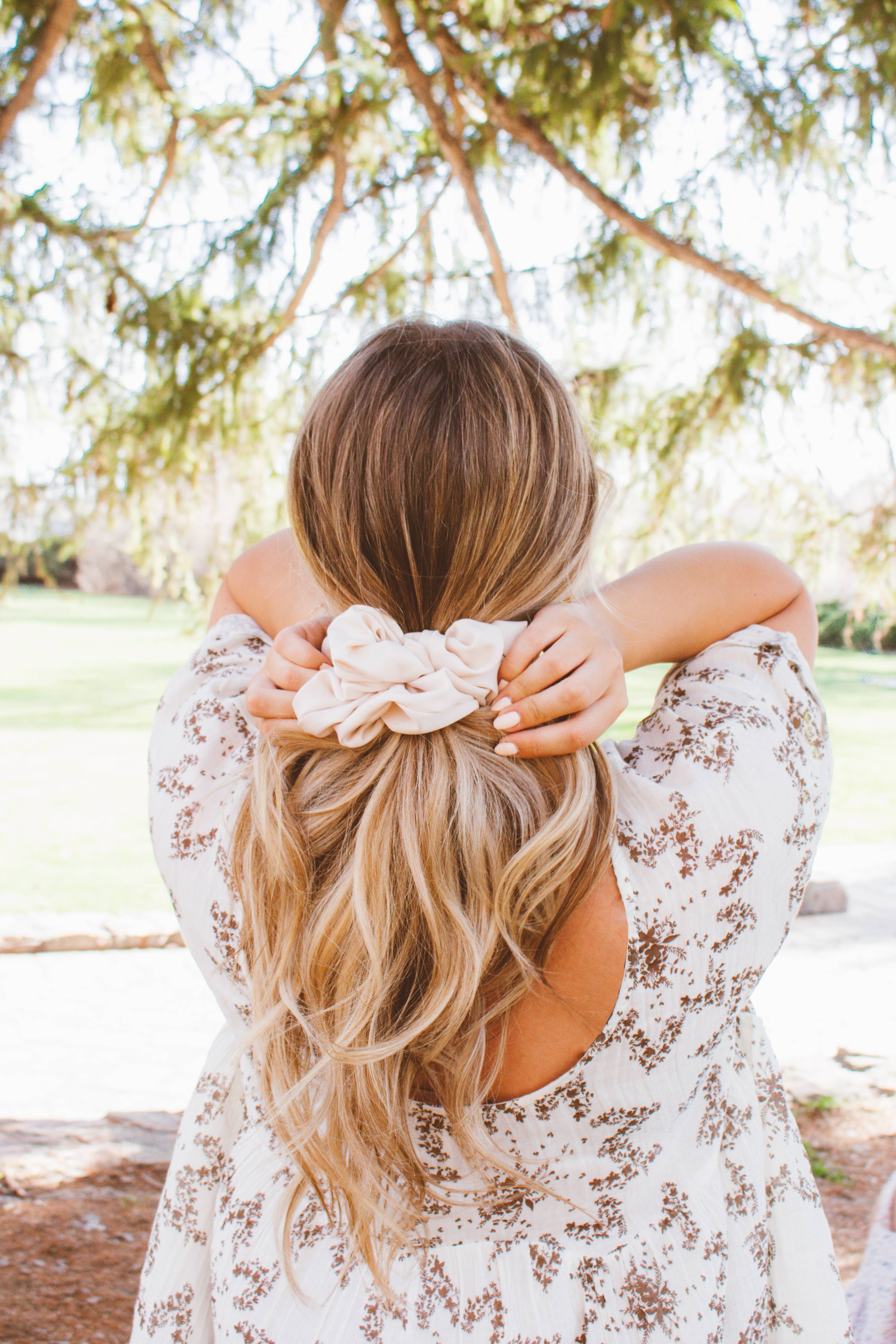 Woman with long blonde hair wearing a floral headband in a park setting
