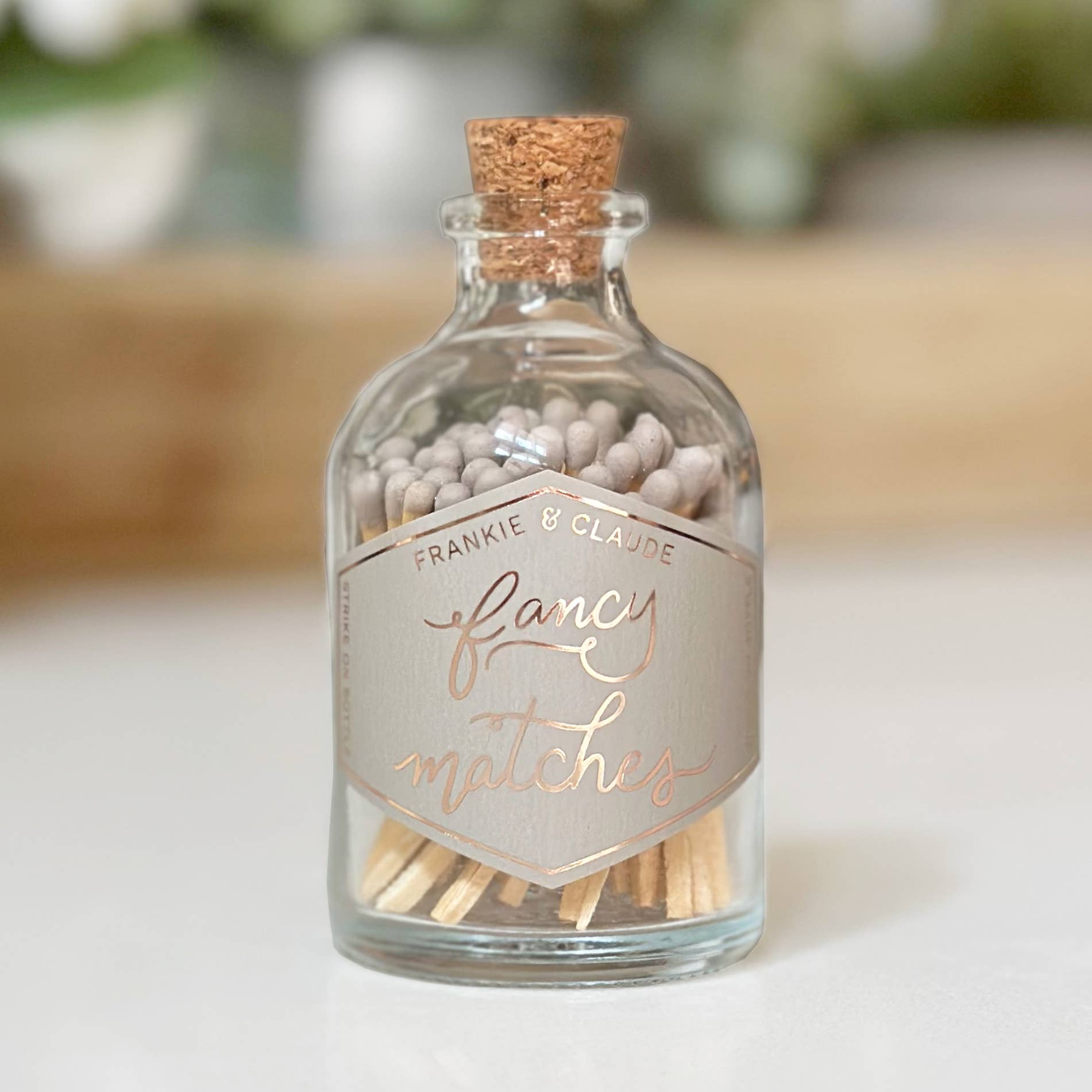 Glass bottle with cork lid containing matches labeled 'Fancy Matches' by Frankie & Claude.