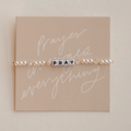 Bracelet with 'PRAY' beads on a beige card with decorative text