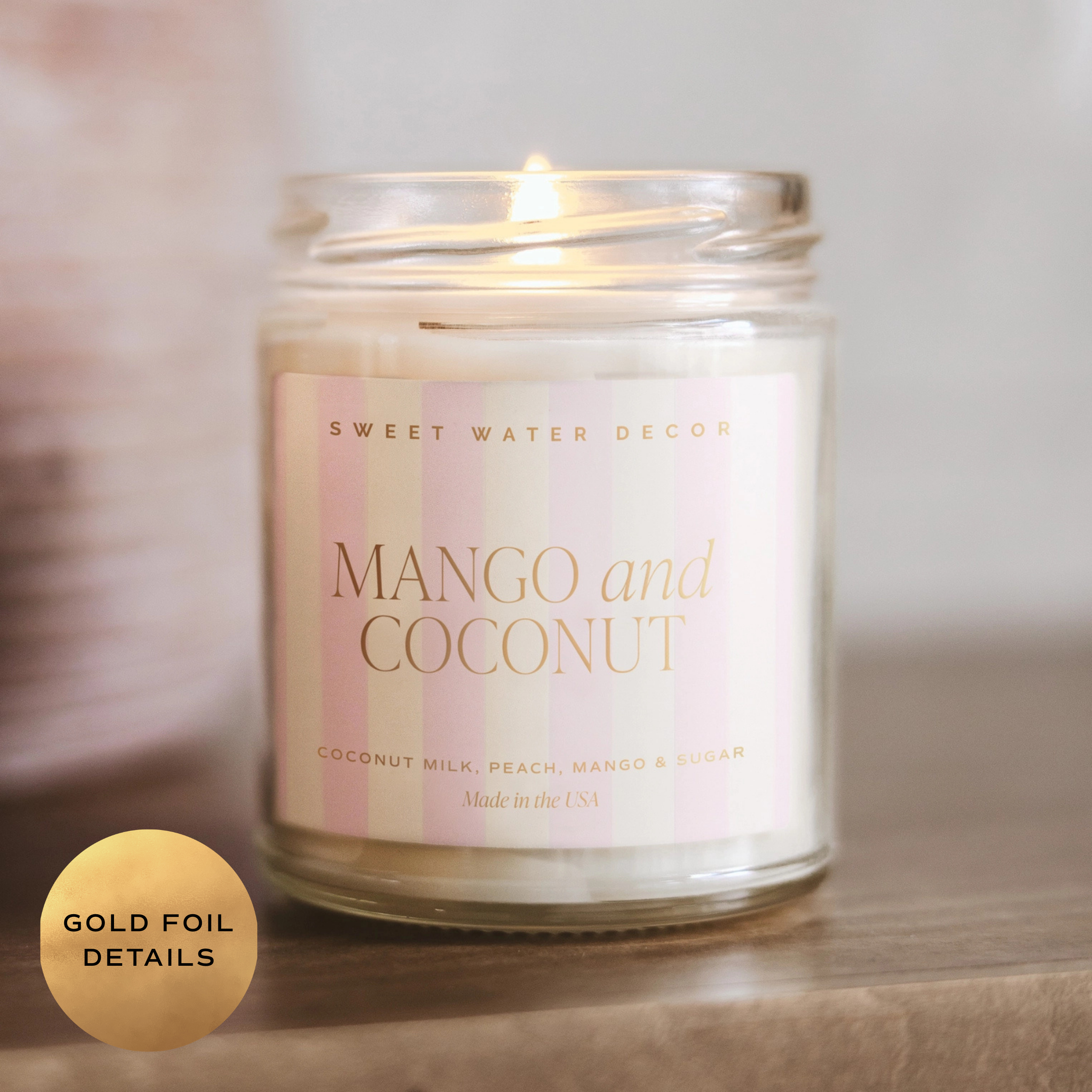 Candle in a glass jar with 'Mango and Coconut' label on a wooden surface