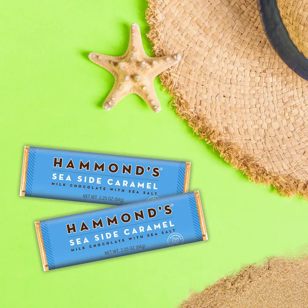 Two Hammond's Sea Side Caramel chocolate bars on a green background with sand and a starfish.