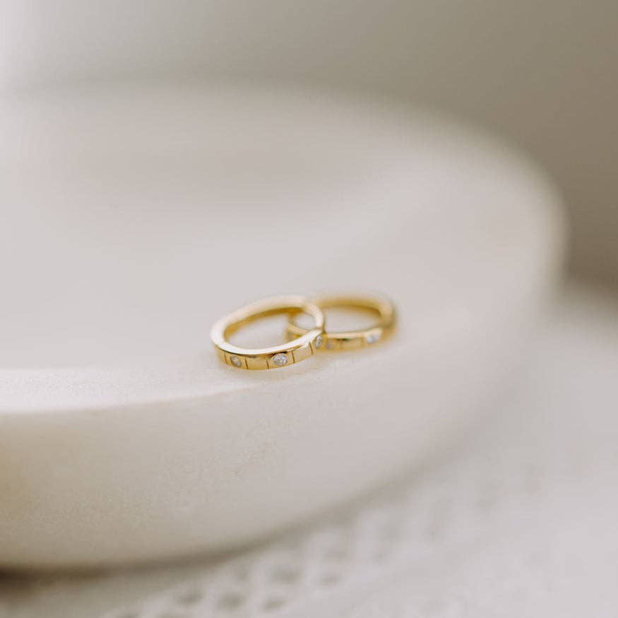 Two gold rings with small diamonds on a light background