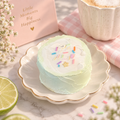 Lime Frosted Cake TABA Squishy with mint-green sides, white frosting and colorful sprinkles, displayed on a scalloped cream plate with gold trim in a pastel pink bakery-inspired setting.