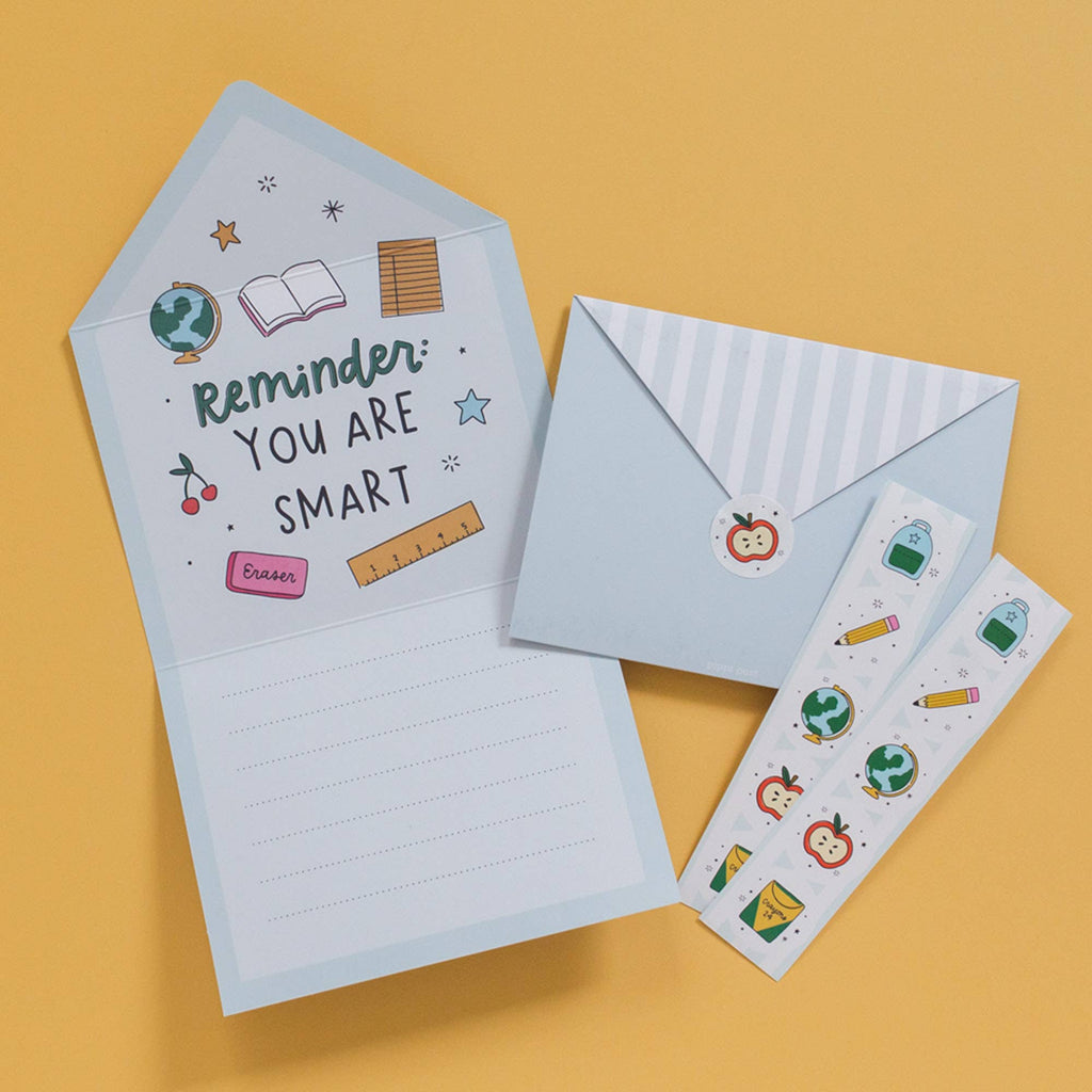 Notebook with motivational quote, envelope, and stickers on a yellow background