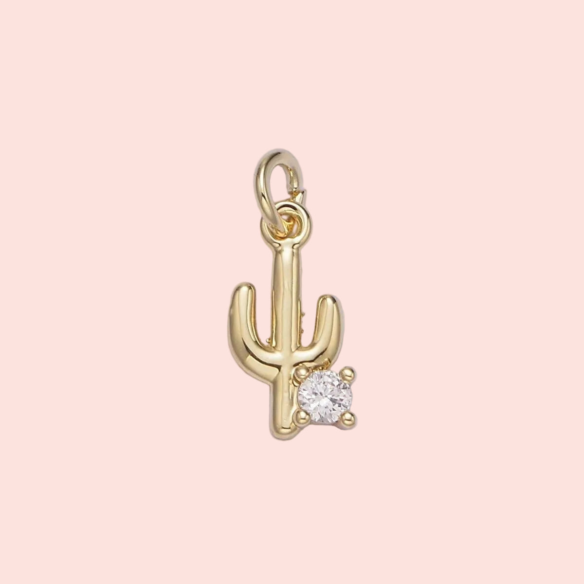 Gold cactus-shaped pendant with a diamond on a light purple background