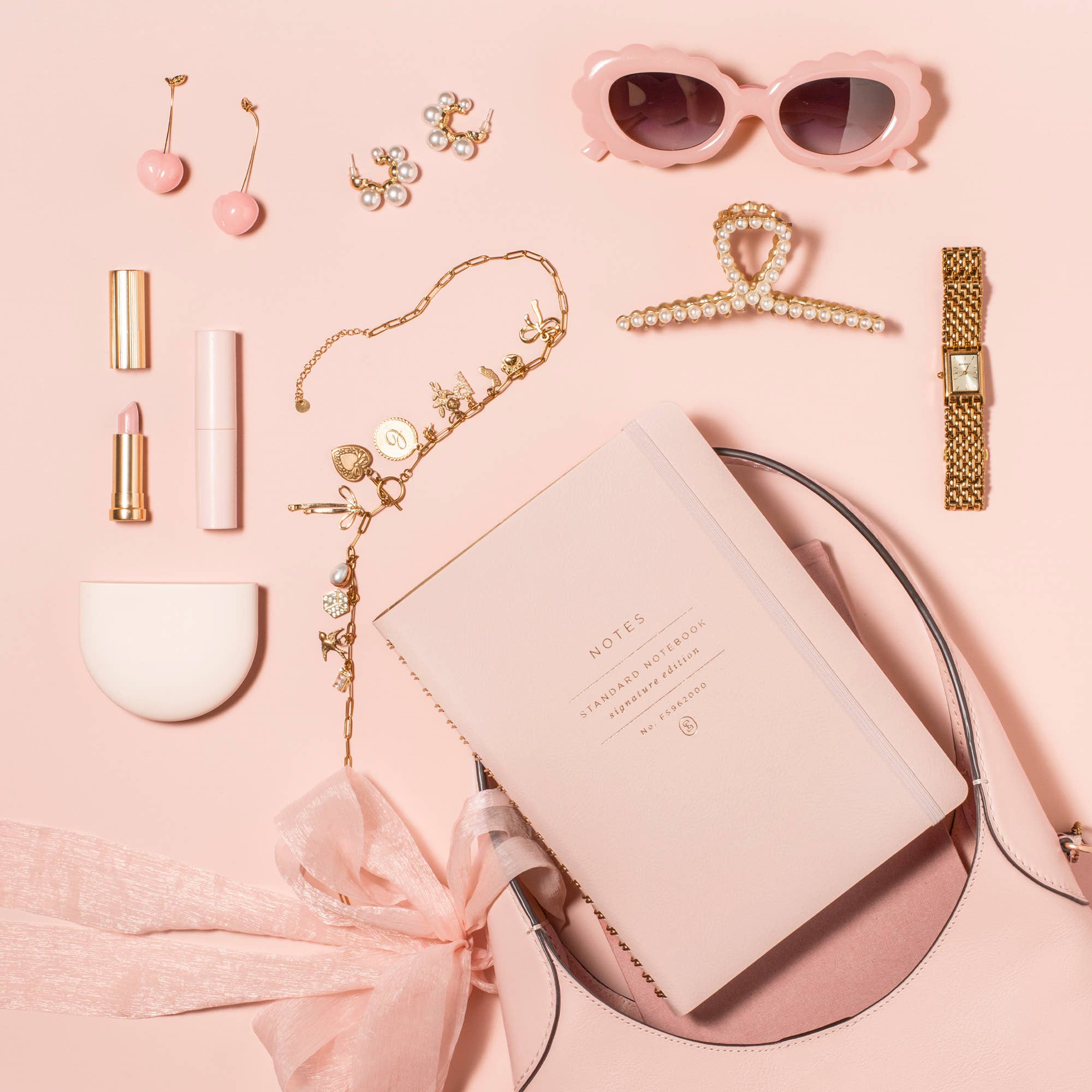 Blush Signature Edition spiral notebook styled with a blush handbag, gold jewelry, pink sunglasses, lipstick, watch, and accessories. A feminine faux leather journal perfect for planning, journaling, work, and everyday inspiration.