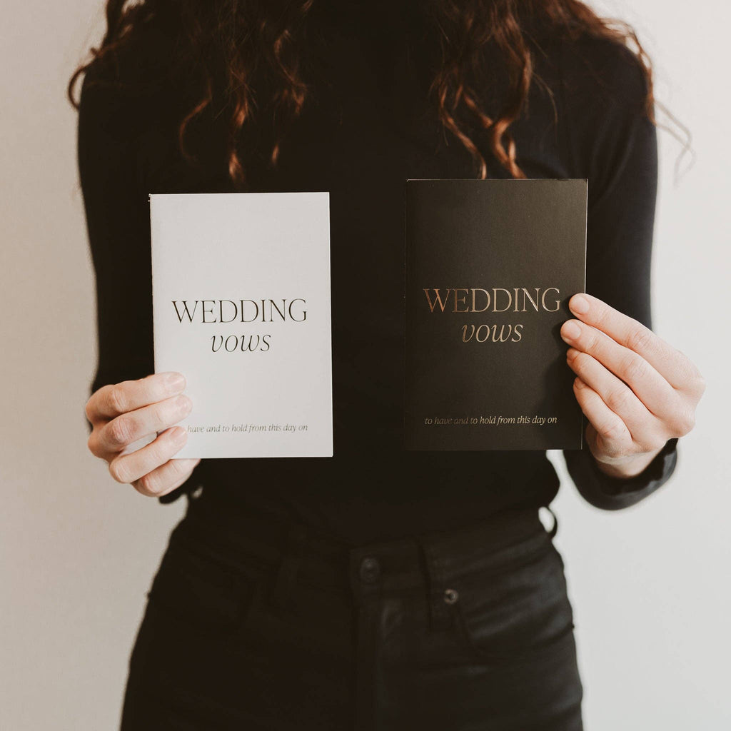 Person holding two books titled 'Wedding Vows' against a neutral background