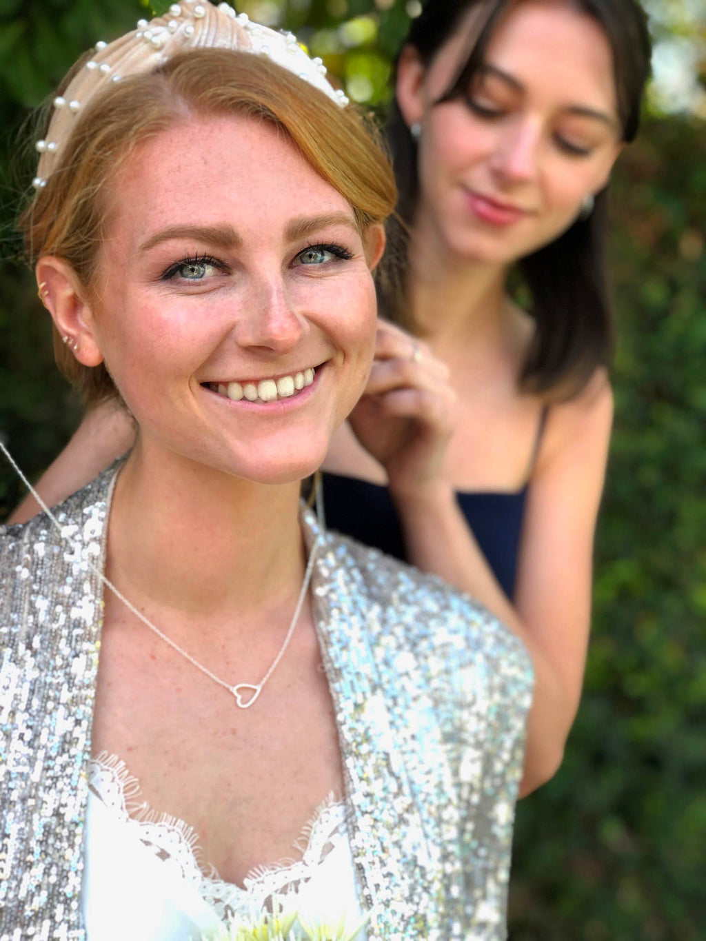 Woman in a silver sequin outfit with a tiara, smiling outdoors.
