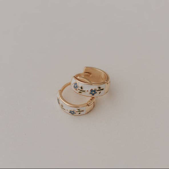Pair of gold hoop earrings with floral designs on a light gray background