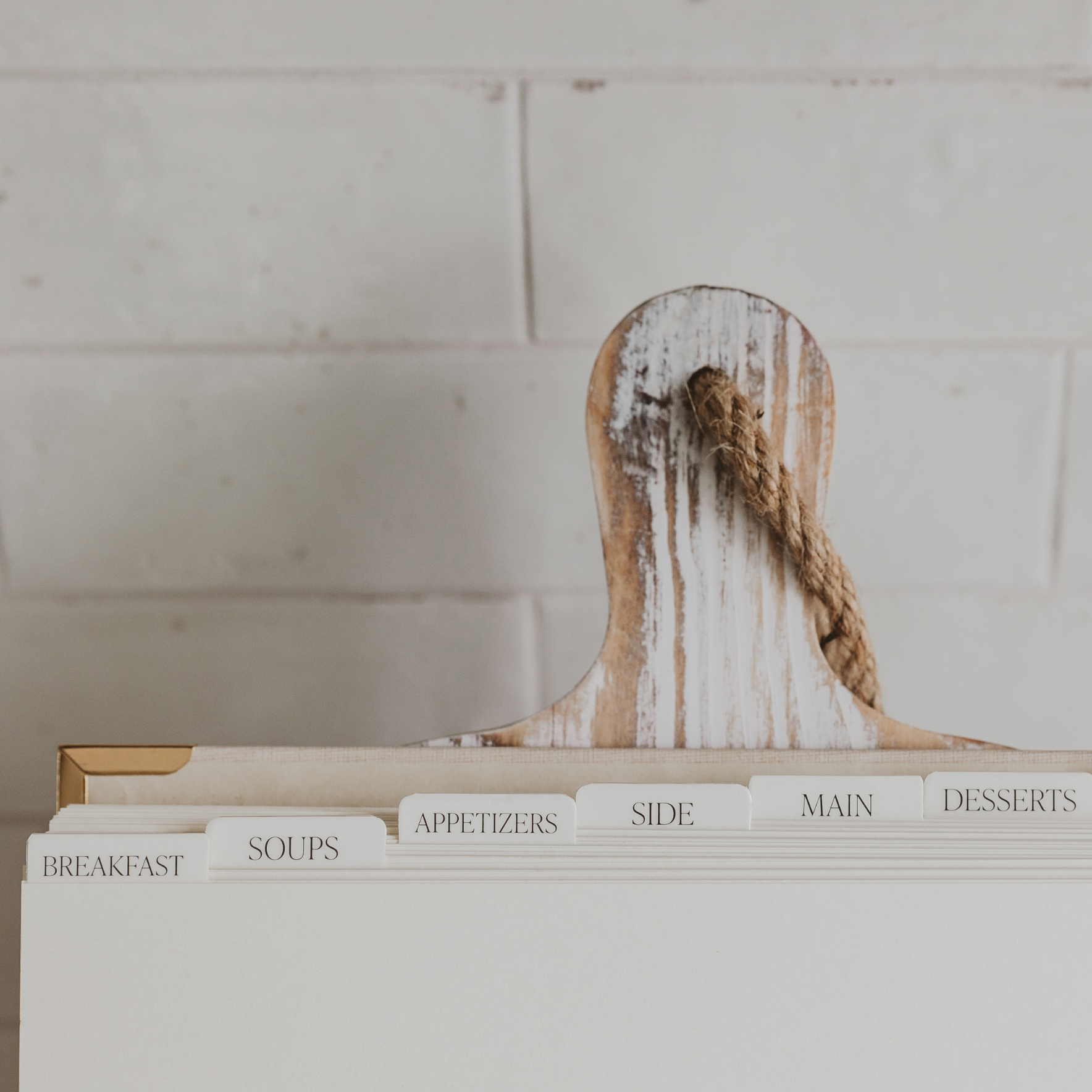 Wooden cutting board with a rustic design on top of a white file folder with category tabs.