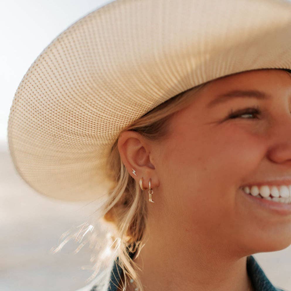 Woman wearing a straw hat and gold earrings with a blurred background
