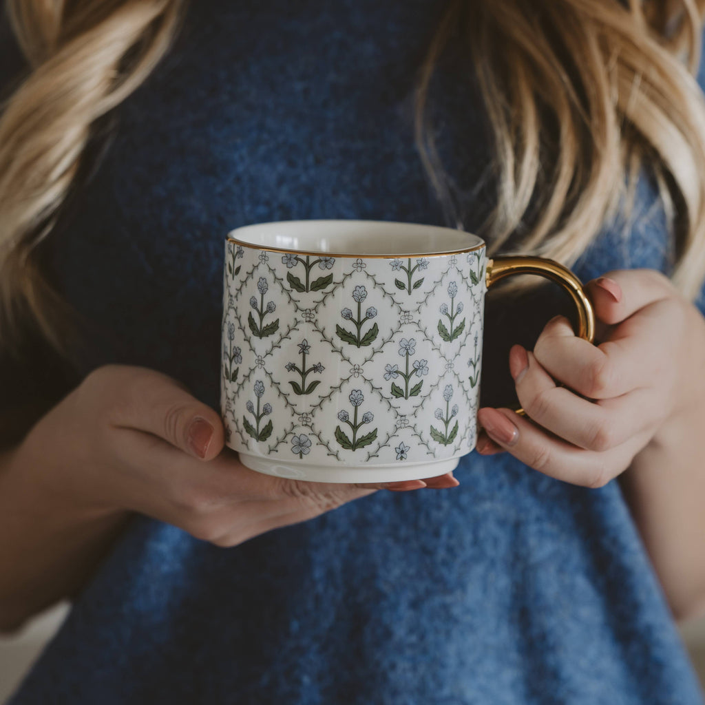 Person holding a patterned mug with a blue dress