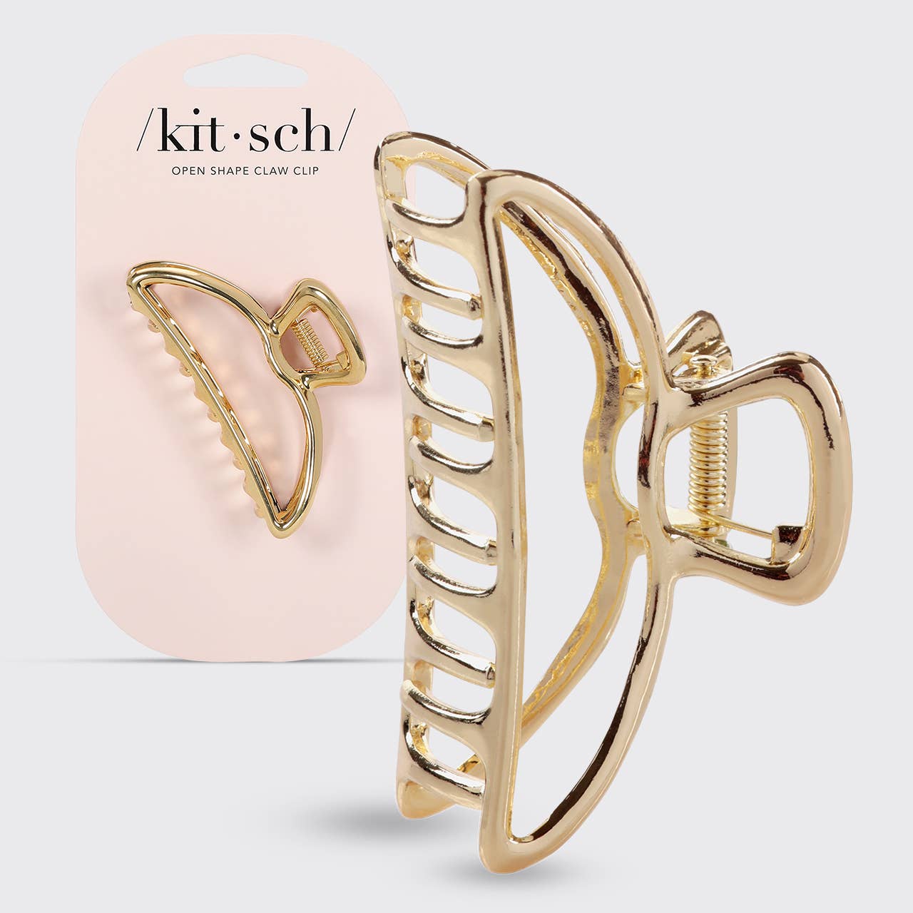 Gold open-shaped claw clip with pink packaging labeled 'kit·sch' on a light gray background