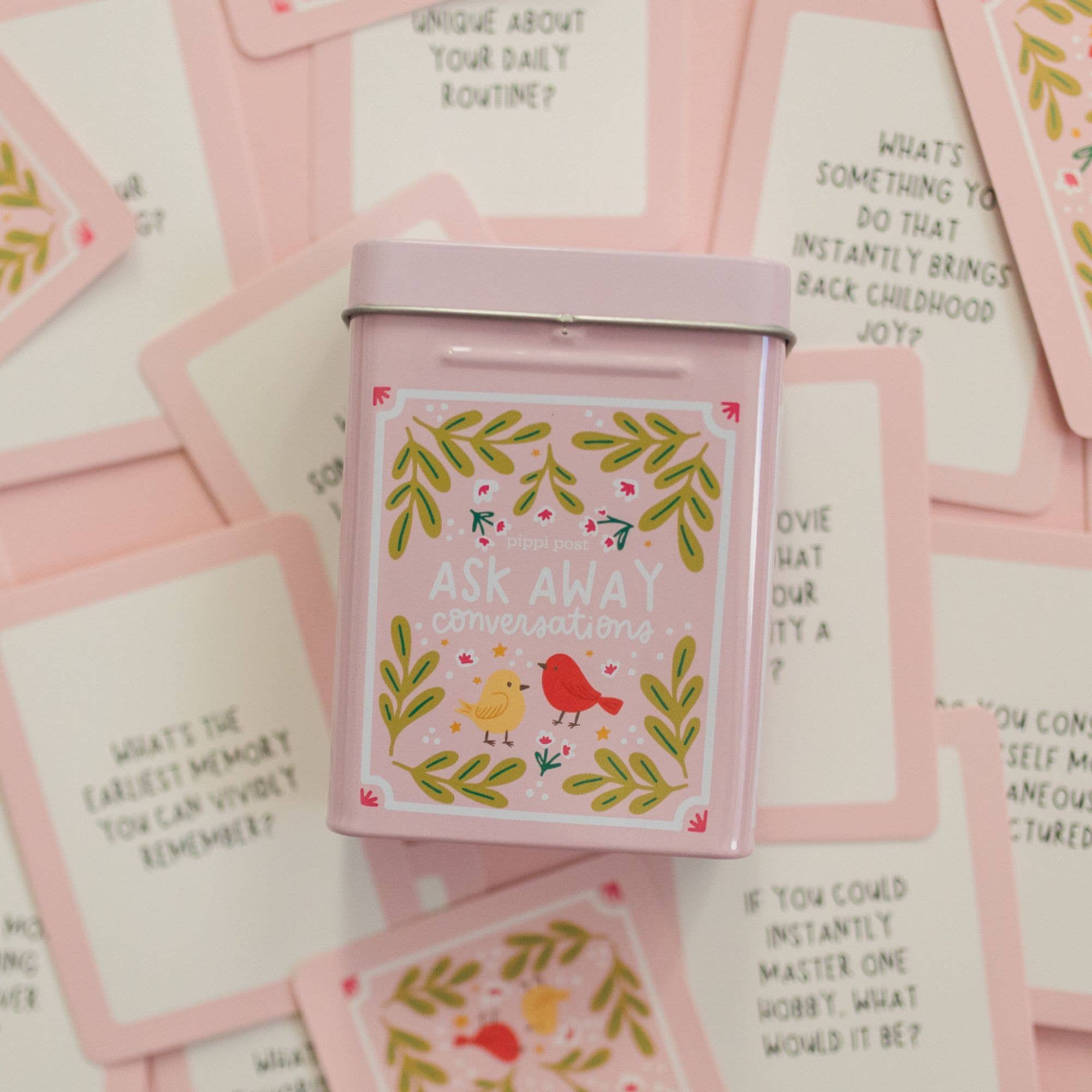 Pink conversation starter box with birds and flowers on a background of pink cards.