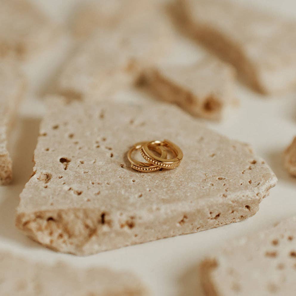 Gold ring on a textured beige stone surface