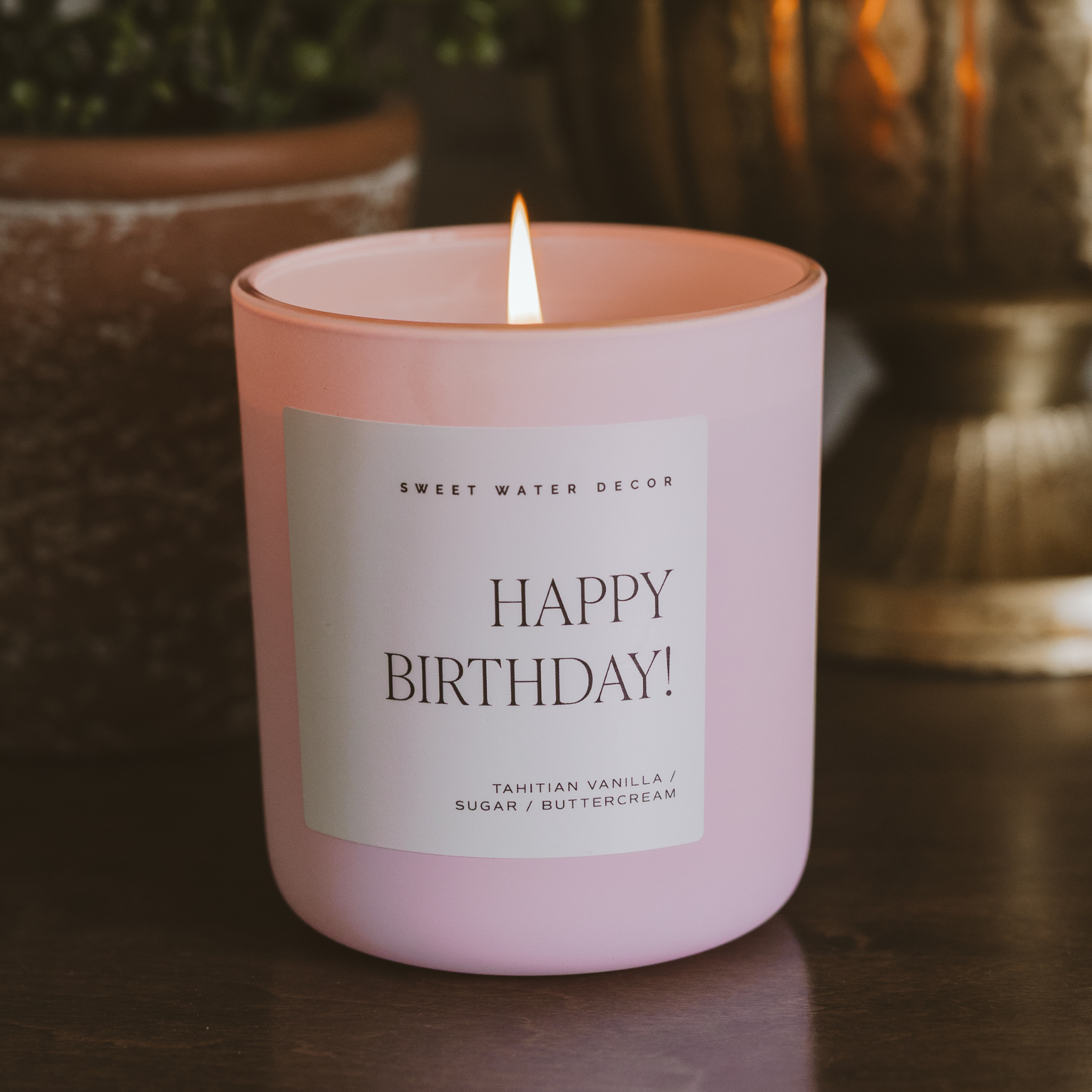 Pink candle with a 'Happy Birthday!' label on a dark surface