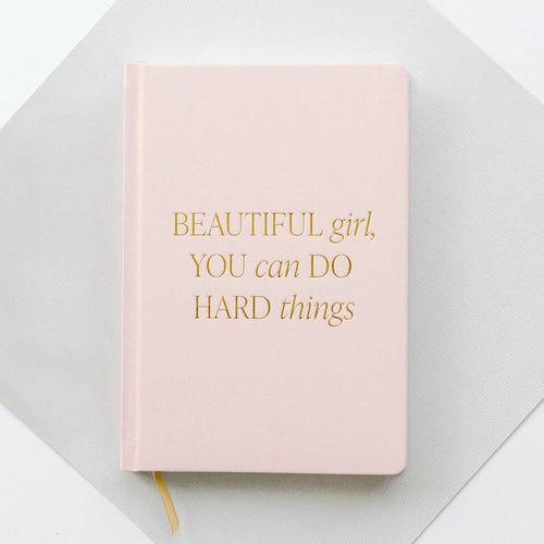 Pink notebook with gold text on a light gray background