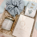 Curated bride-to-be gift box featuring a Something Blue soy candle, embroidered bride socks, powder blue jumbo scrunchie, gold diamond pen, and keepsake vow books, beautifully arranged in a cream magnetic gift box with crinkle paper.