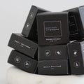 Stack of black 'Daily Rhythms' shower steamers on a white marble surface