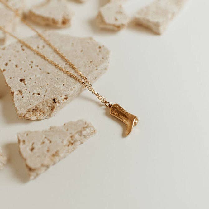 Gold necklace with a boot-shaped pendant on a light background