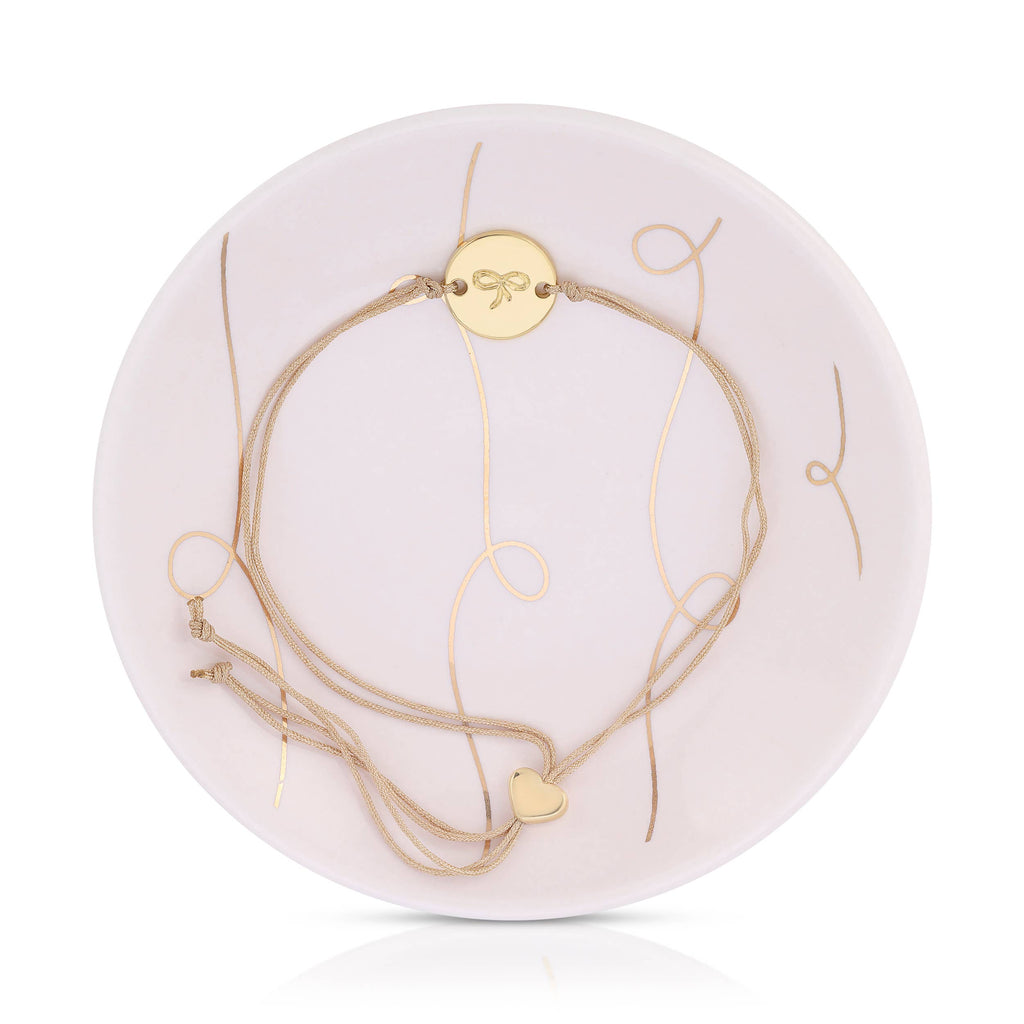 Set of gold necklaces on a white circular stand with a brand logo.