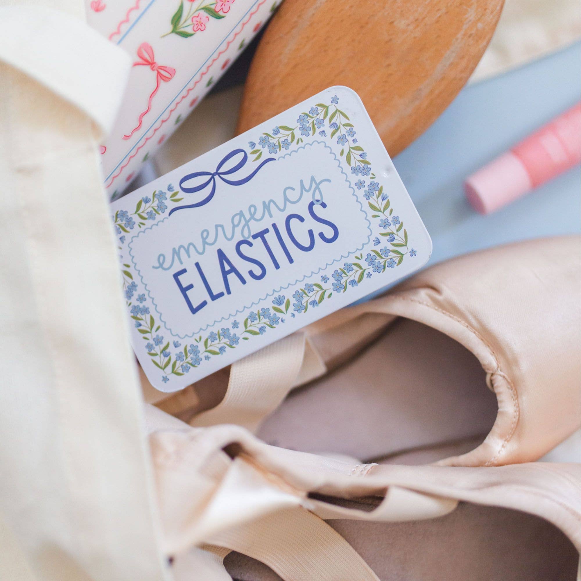 Ballet shoes with a 'emergency elastics' label and a wooden spatula.