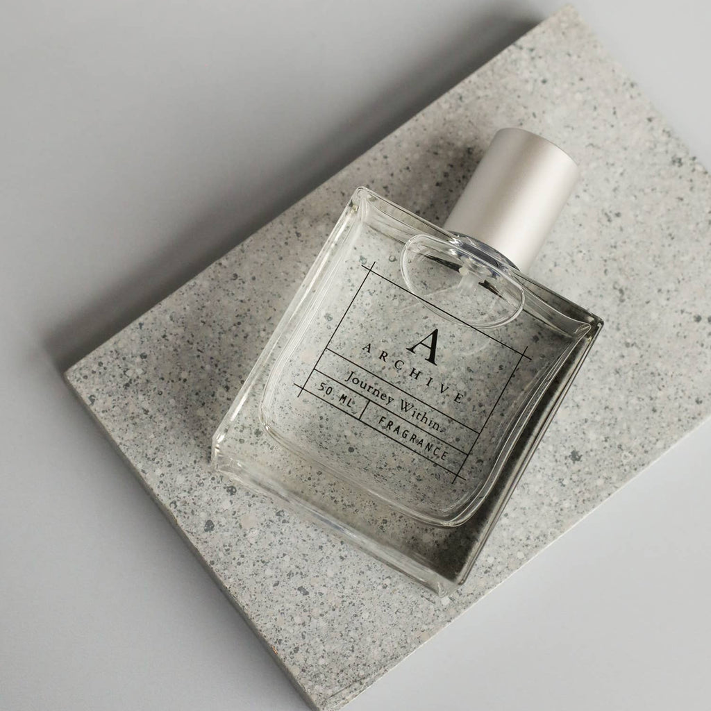 Perfume bottle on a textured stone surface with a neutral background