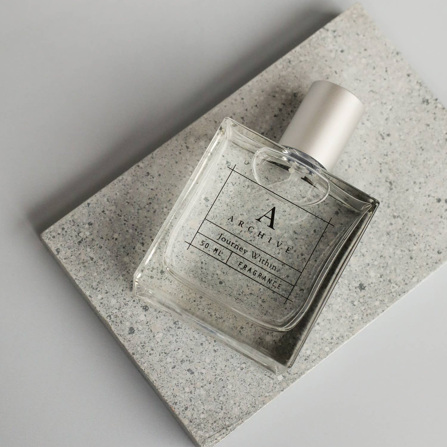 Perfume bottle on a textured stone surface with a neutral background
