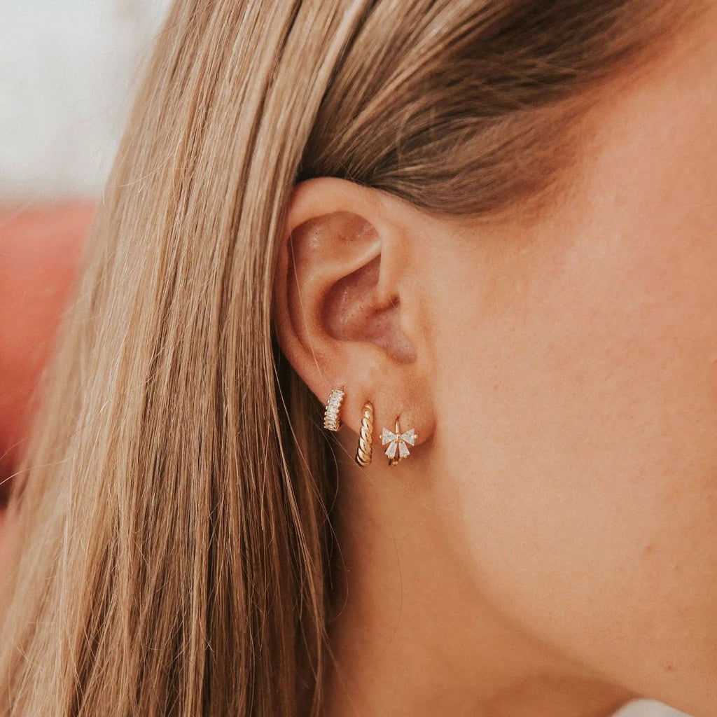 Close-up of a person wearing gold hoop earrings with a blurred background