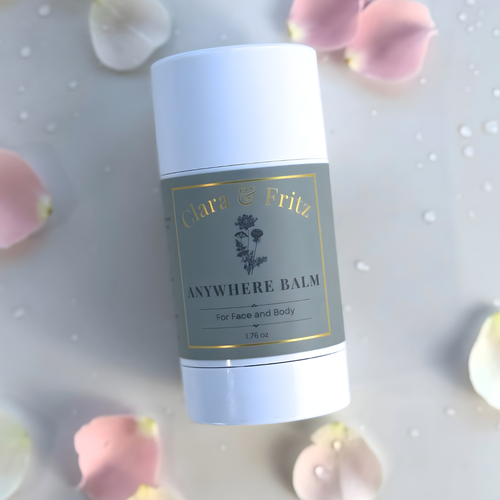 Balm container with 'Clara & Fritz' branding on a soft, blurred background with flowers.