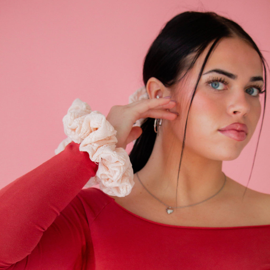Woman wearing a red top with white cuffs against a pink background