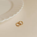 Two gold rings on a beige surface with a soft focus background