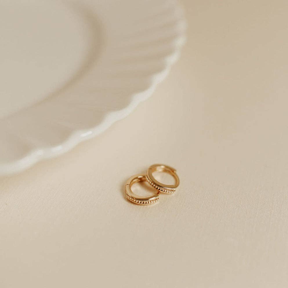 Two gold rings on a beige surface with a soft focus background