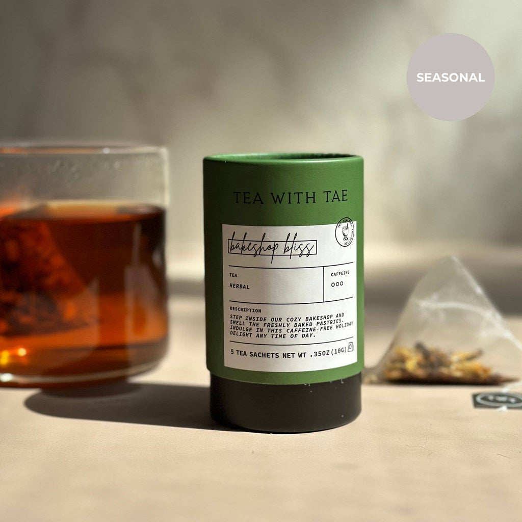 Tea packaging with a glass of tea and loose tea leaves on a neutral background