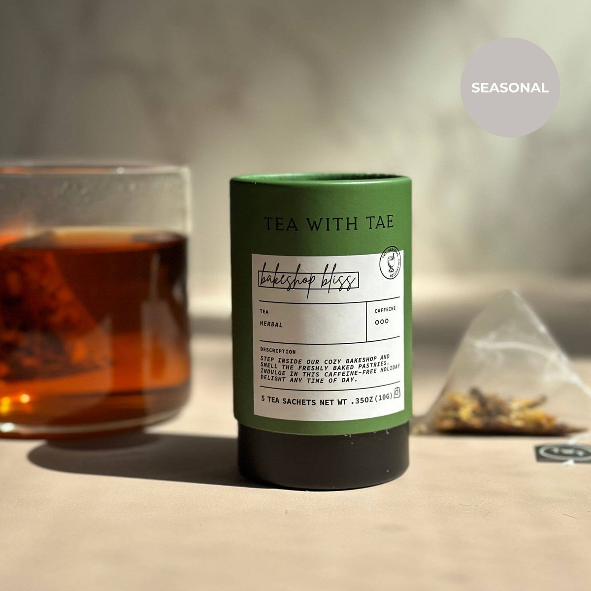 Tea packaging with a glass of tea and loose tea leaves on a neutral background