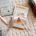 Dark chocolate almond bar, pink pen, and gift tags on a textured surface