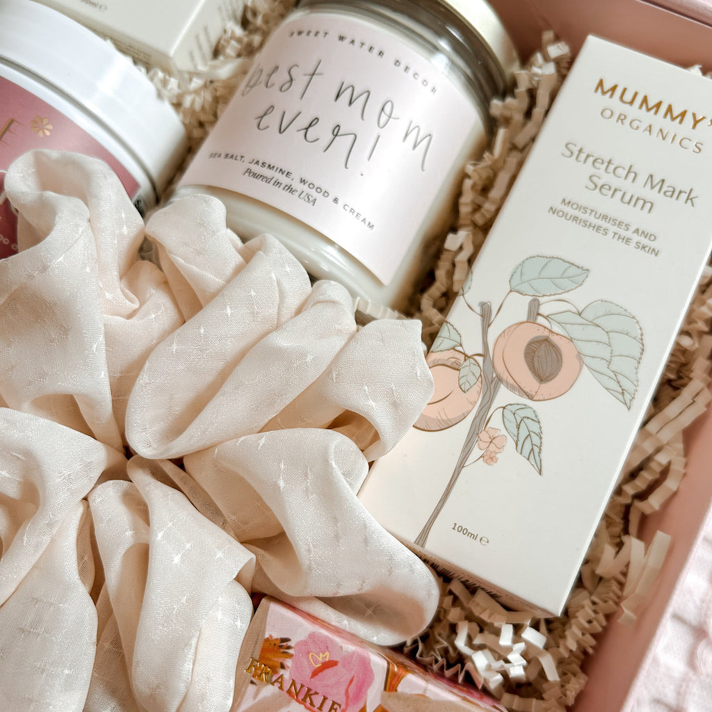 Gift set with skincare products and a candle labeled 'Best Mom Ever' in a box.