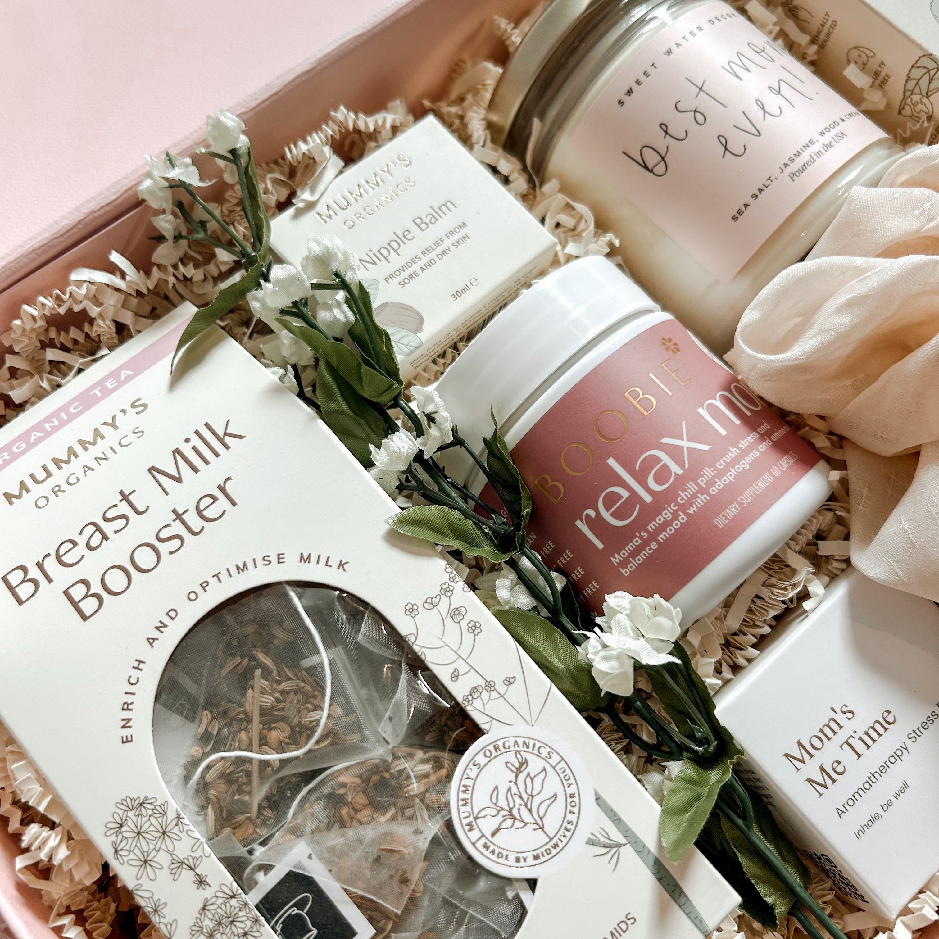Gift set with breast milk booster, candles, and other products in a pink box.