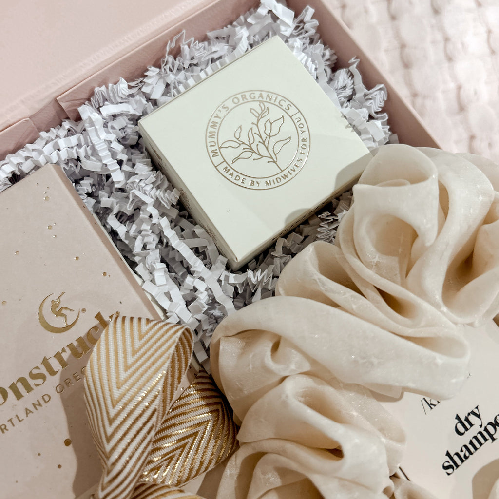 Product packaging with a soap bar and scrunchies on a soft pink background