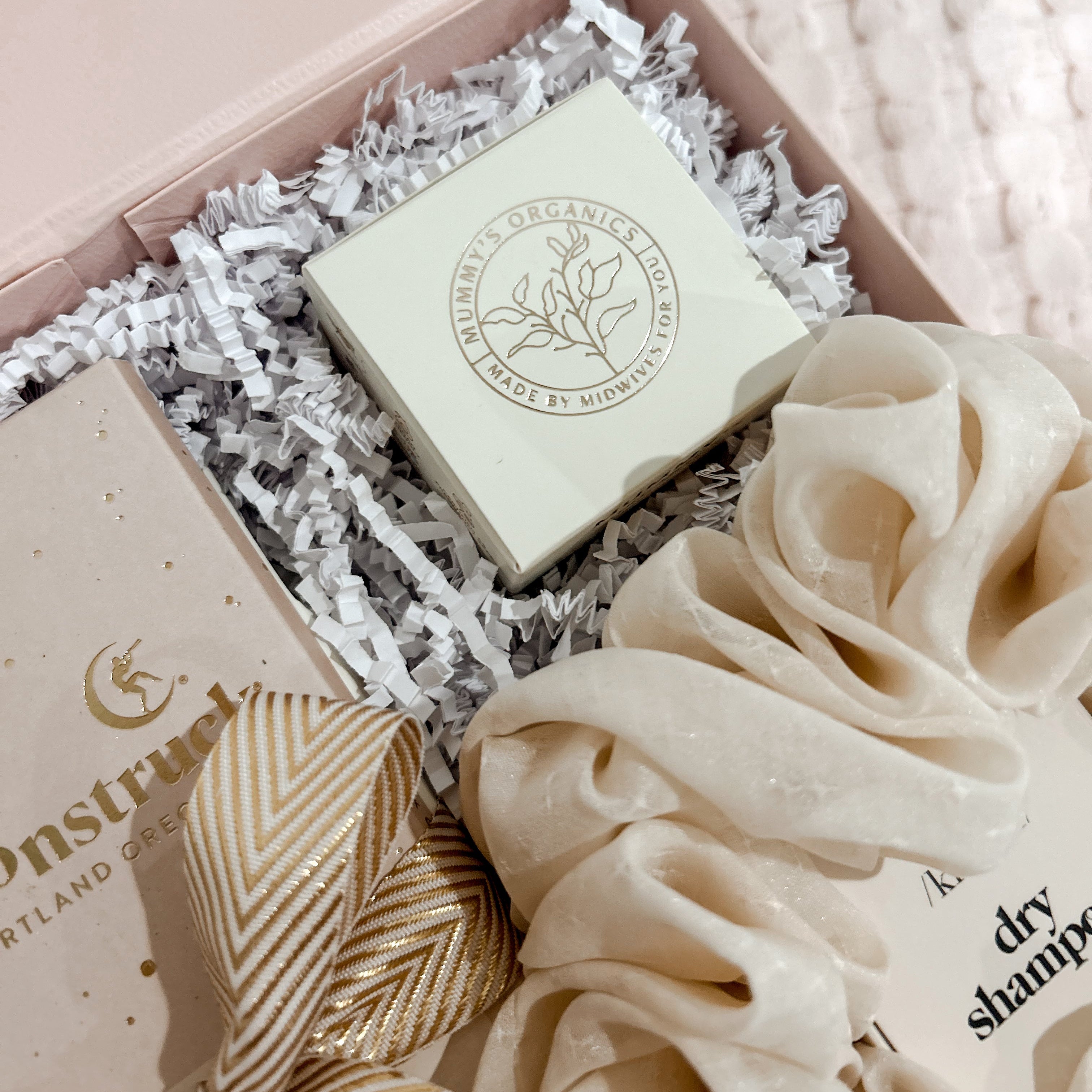 Product packaging with a soap bar and scrunchies on a soft pink background