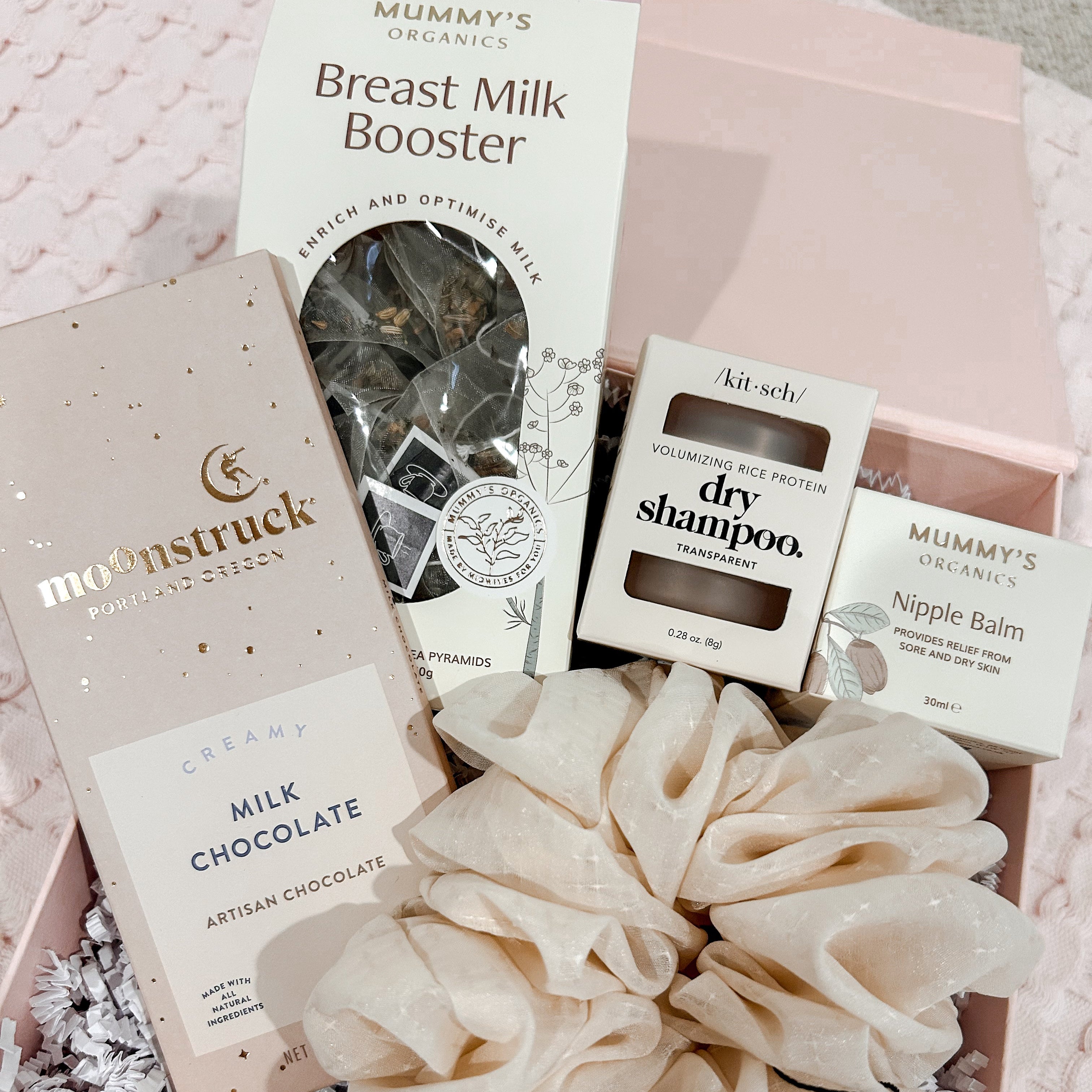 Collection of organic products including a breast milk booster, chocolate, and skincare items in a box.