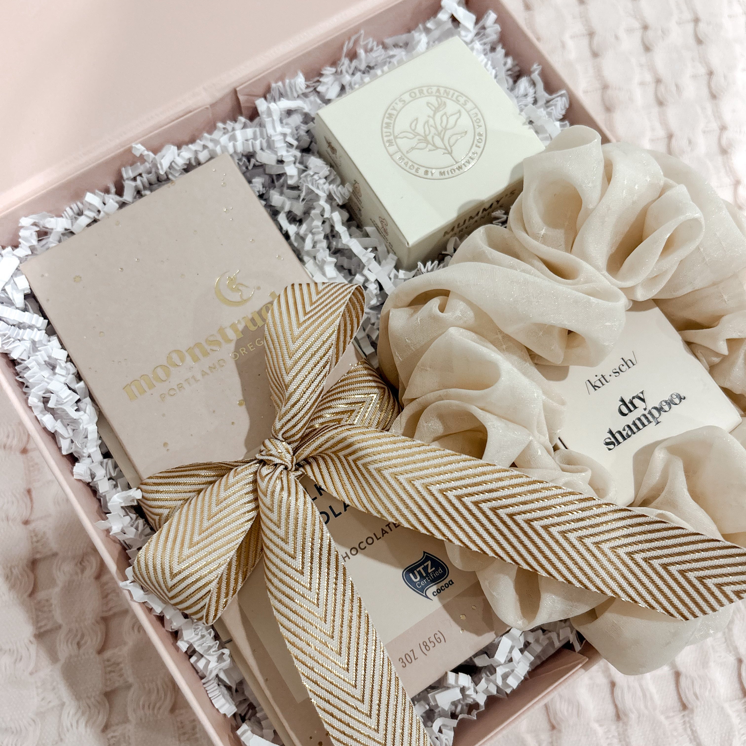 Gift box with soap, bow, and hair scrunchies on a textured surface