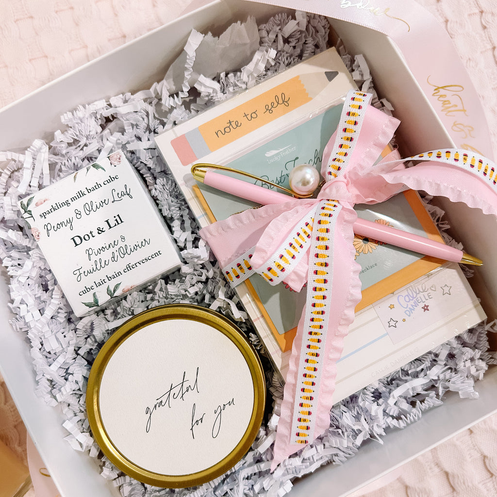 Gift box with a jar, card, and headband on a soft pink background