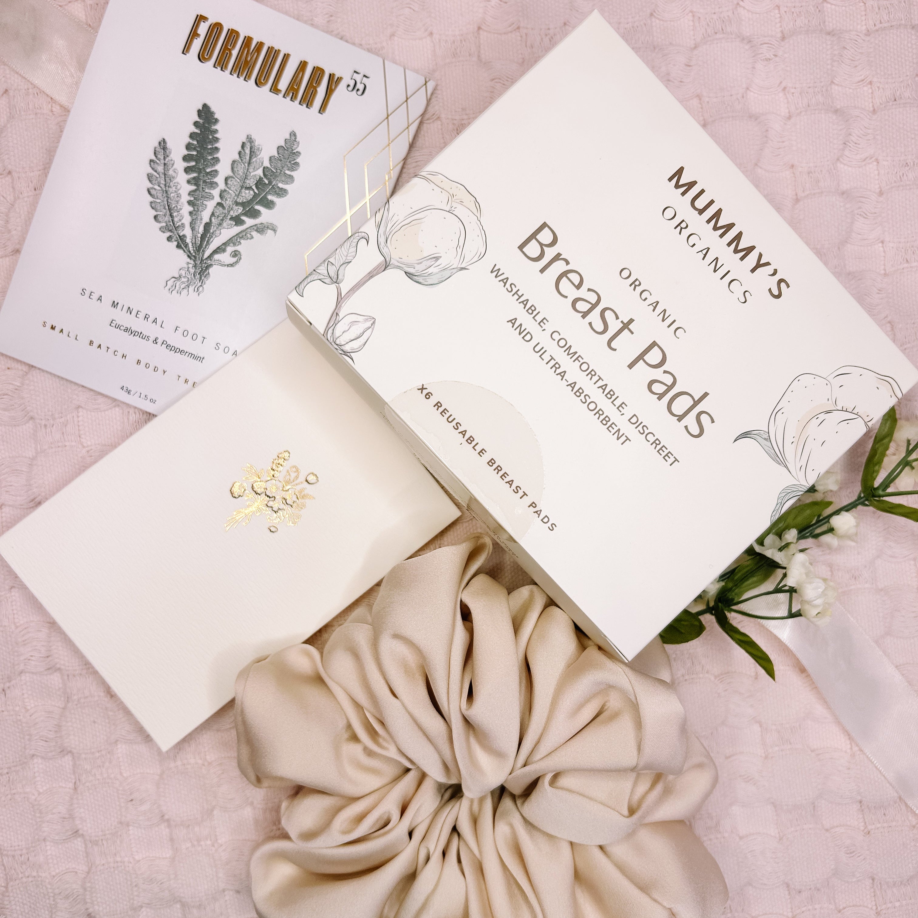 Mummy's Organics breast pads with packaging on a pink floral background