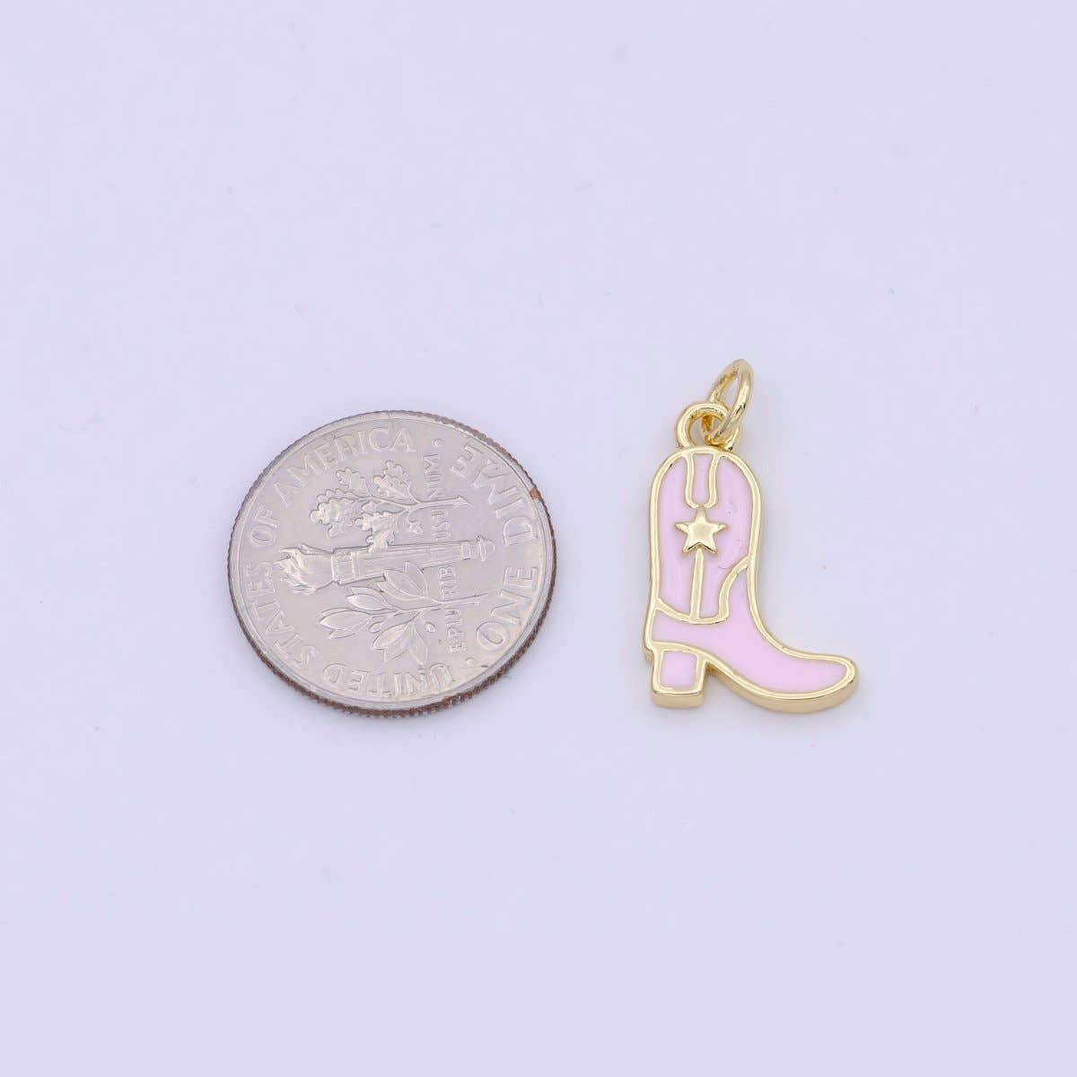Pink cowboy boot charm next to a quarter on a light purple background