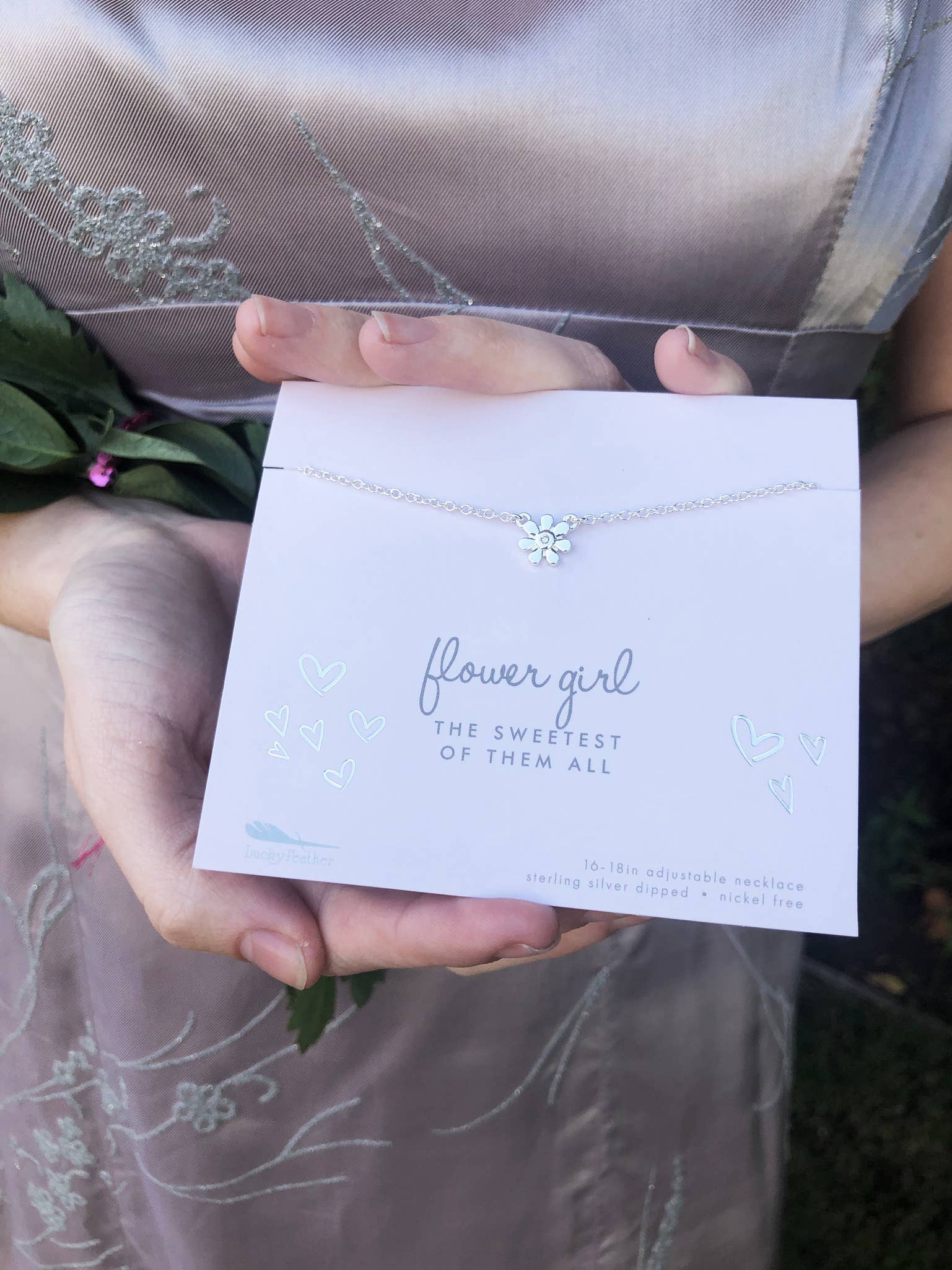 Necklace with a card labeled 'flower girl' held by a person.