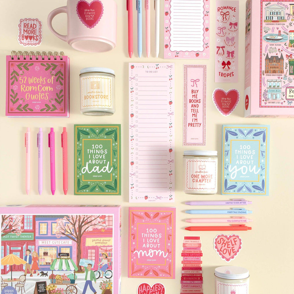 Collection of stationery items including notebooks, candles, and pens on a light background