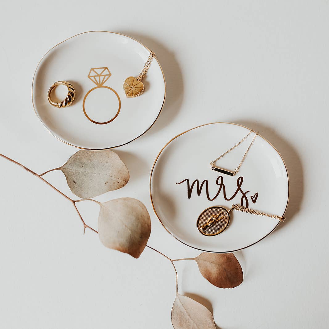 Two white ceramic dishes with jewelry on a light background