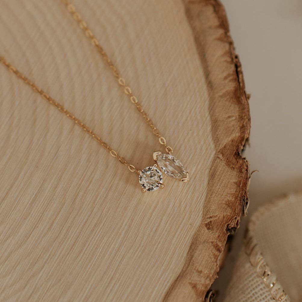 Gold necklace with two diamond pendants on a wooden surface